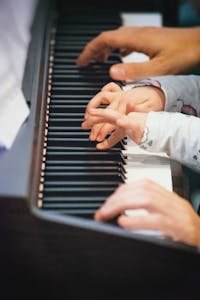 A close-up view of child and adult hands playing the piano in Berlin, Germany.