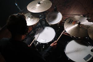 An overhead shot capturing a drummer with drumsticks playing a drum set in a studio.