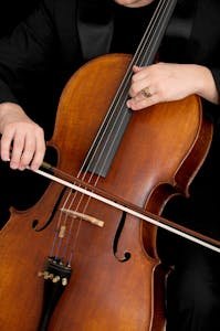 Detailed view of a musician playing the cello with focus on strings and bow.